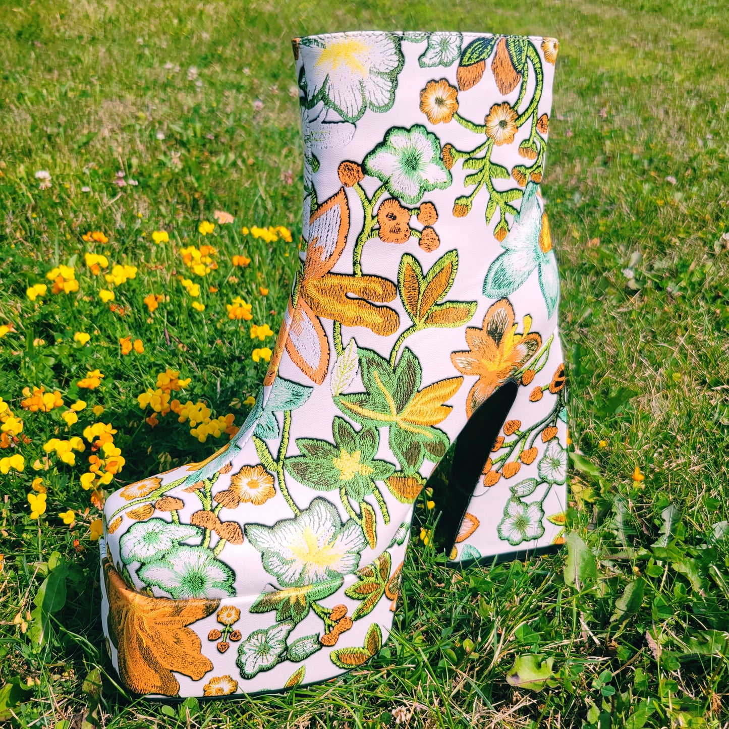 Retro 70's Platform ankle boots with orange and green floral print. Boot on the grass next to buttercup flowers.